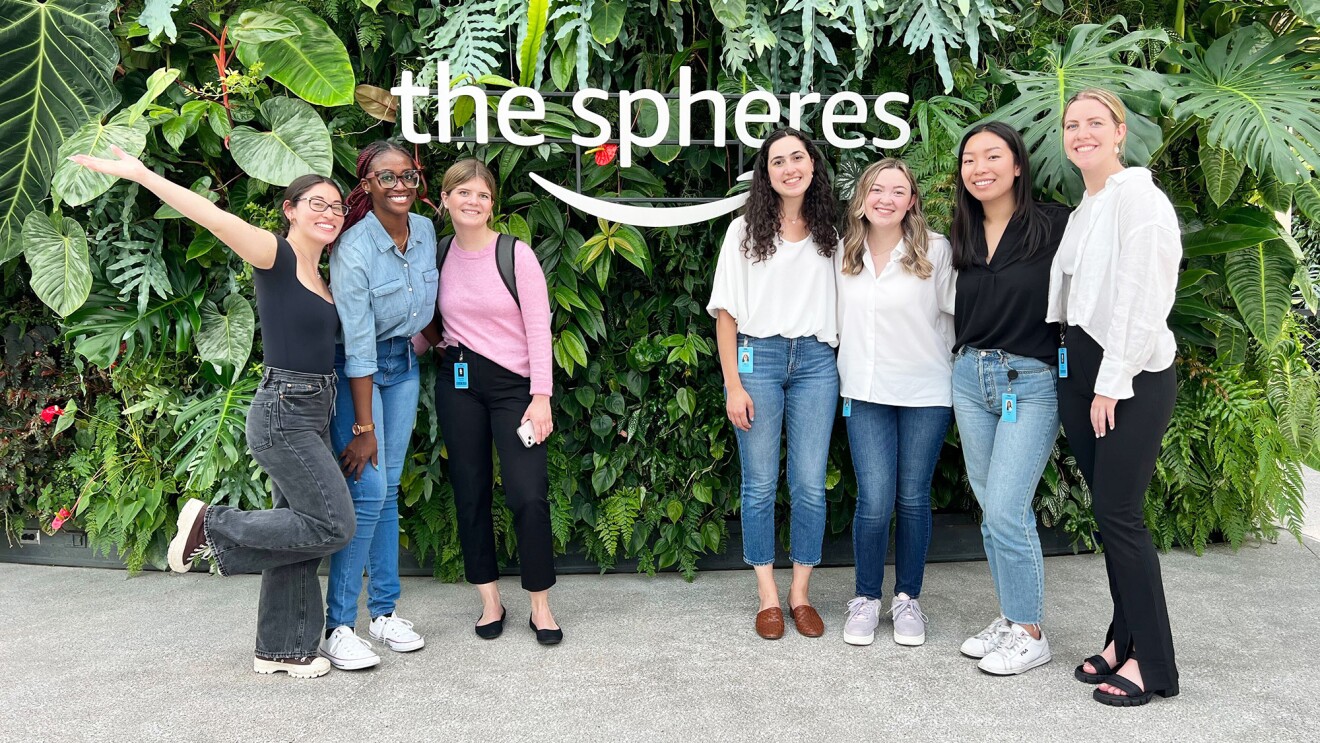 Seven interns smile as they stand in front of The Spheres' greenery-filled wall.