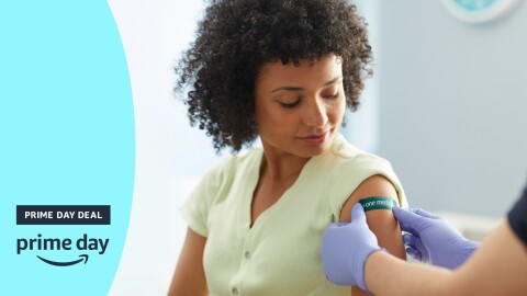 一个女人看着她的左臂的形象作为一个护士把绿色医疗急救绷带。左边是一个蓝色的旗帜说'天交易和'一天