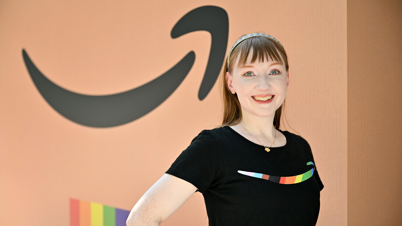 茶色の段ボール色のパネルの前に立つ黒いTシャツを着た髪の長い女性