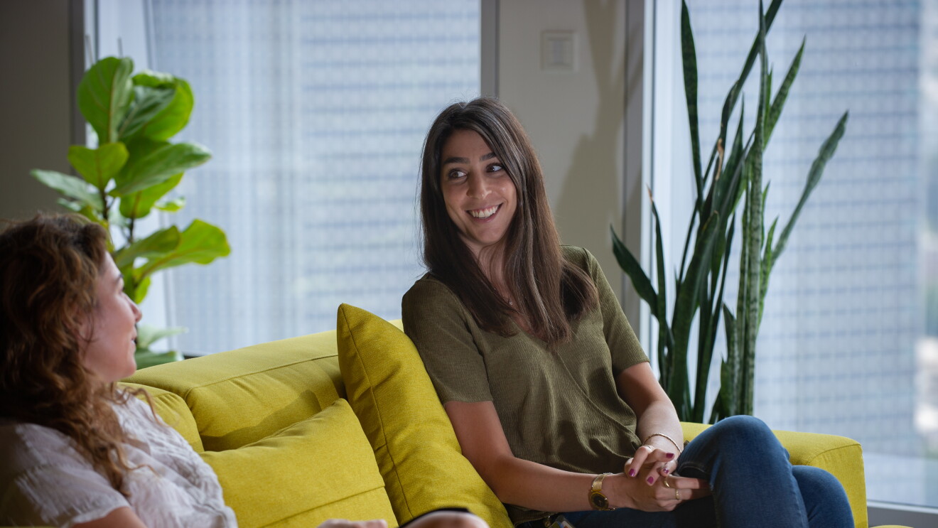 Amazon employee sat on yellow sofa talking with colleague 