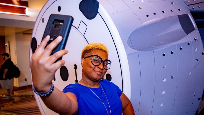 An image of a woman taking a selfie photo in front of the space shuttle mockup at re:MARS 2022.