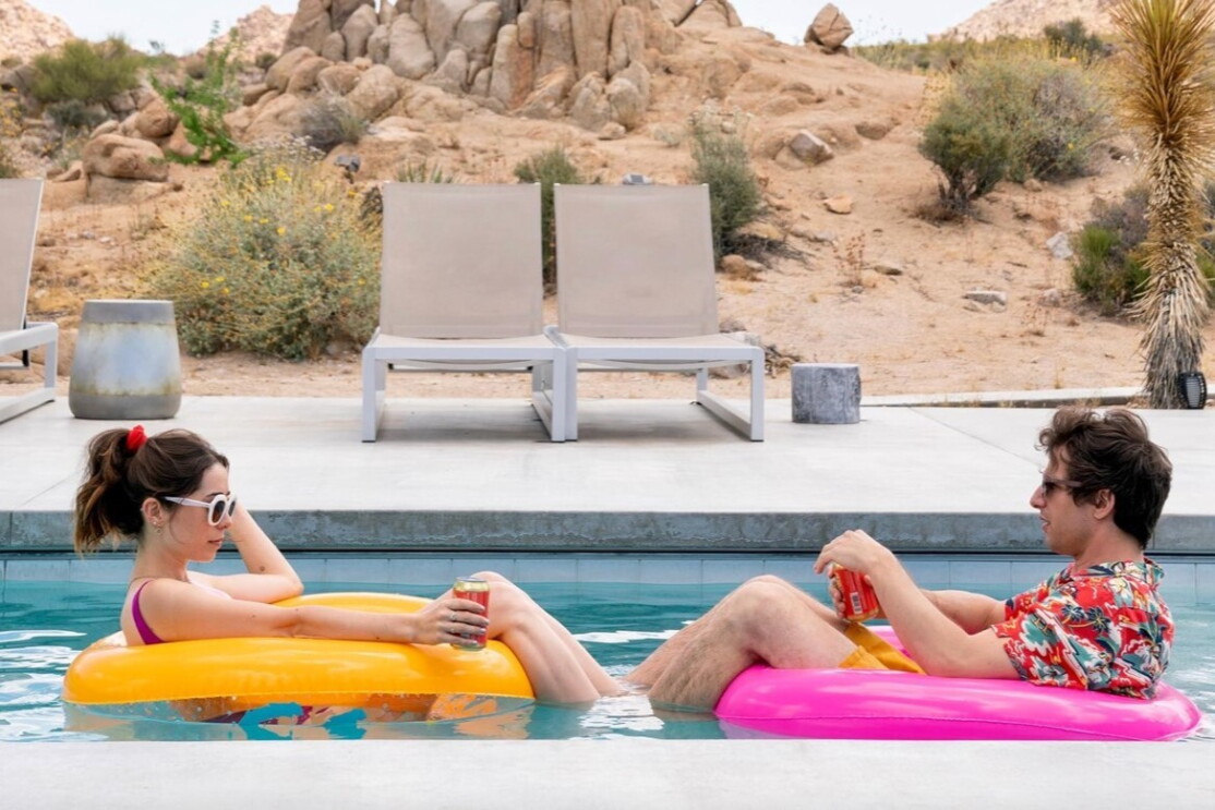 A man and a woman sit pool inflatables in a swimming pool