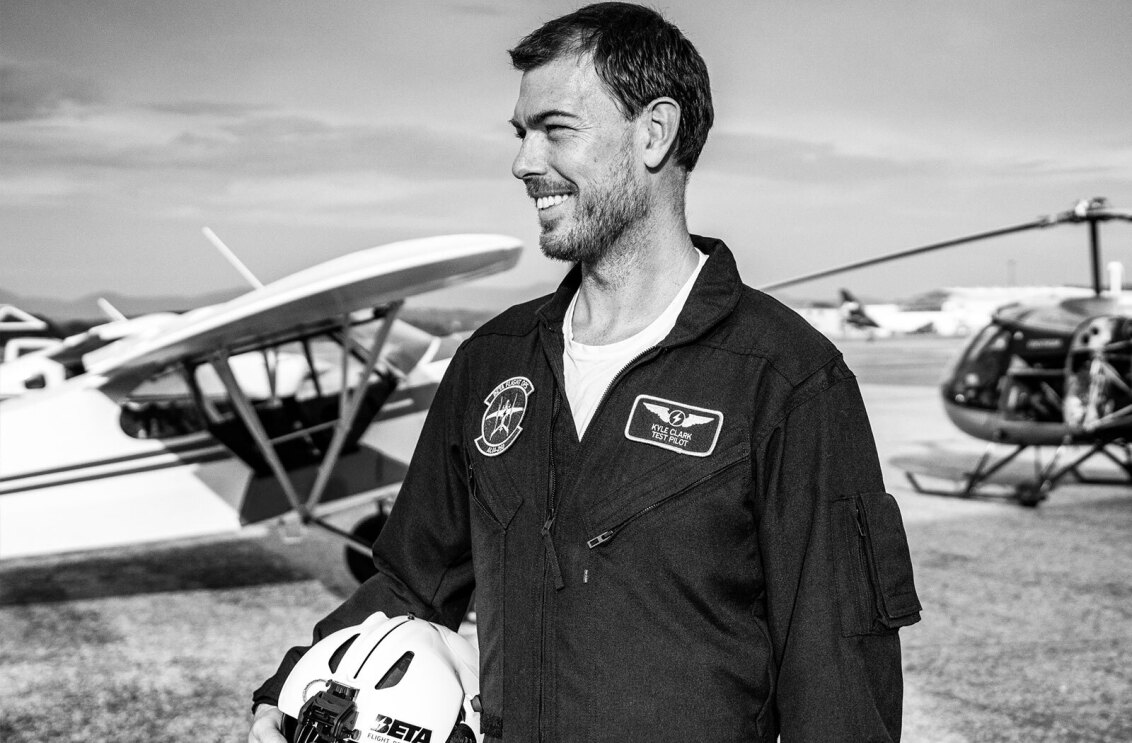 Founder and CEO of Beta Technologies, Kyle Clark, standing in front of an airplane and a helicopter.