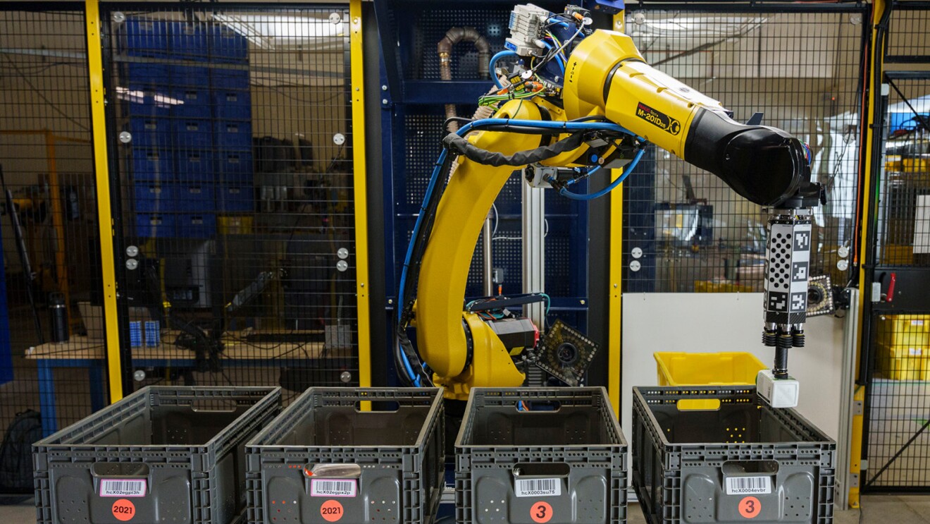 A robotic arm moves products from a bin in an Amazon fulfillment center.