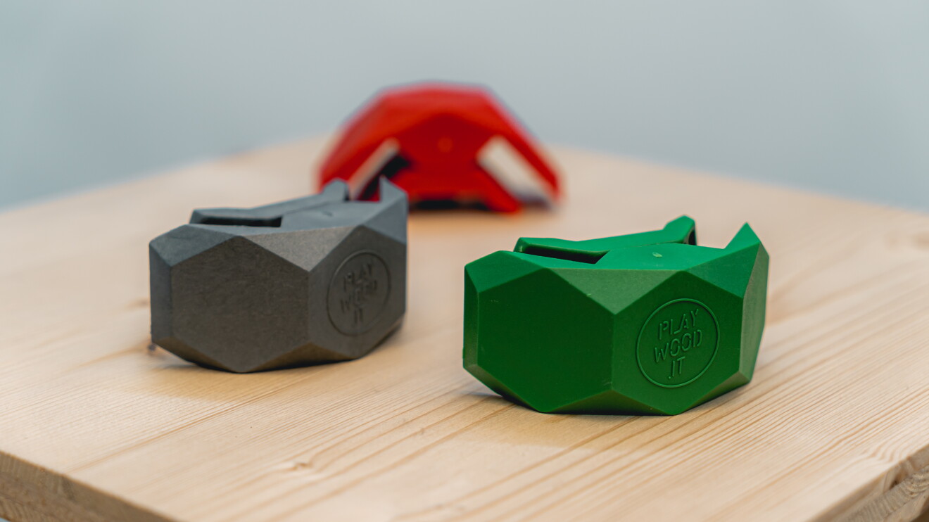 Tre morsetti Playwood in verde, grigio e rosso su una superficie di legno