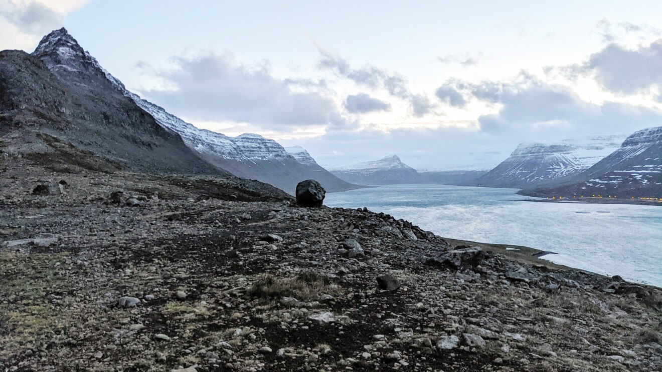 An image a lake in Iceland surrounded by mountains covered in snow. 