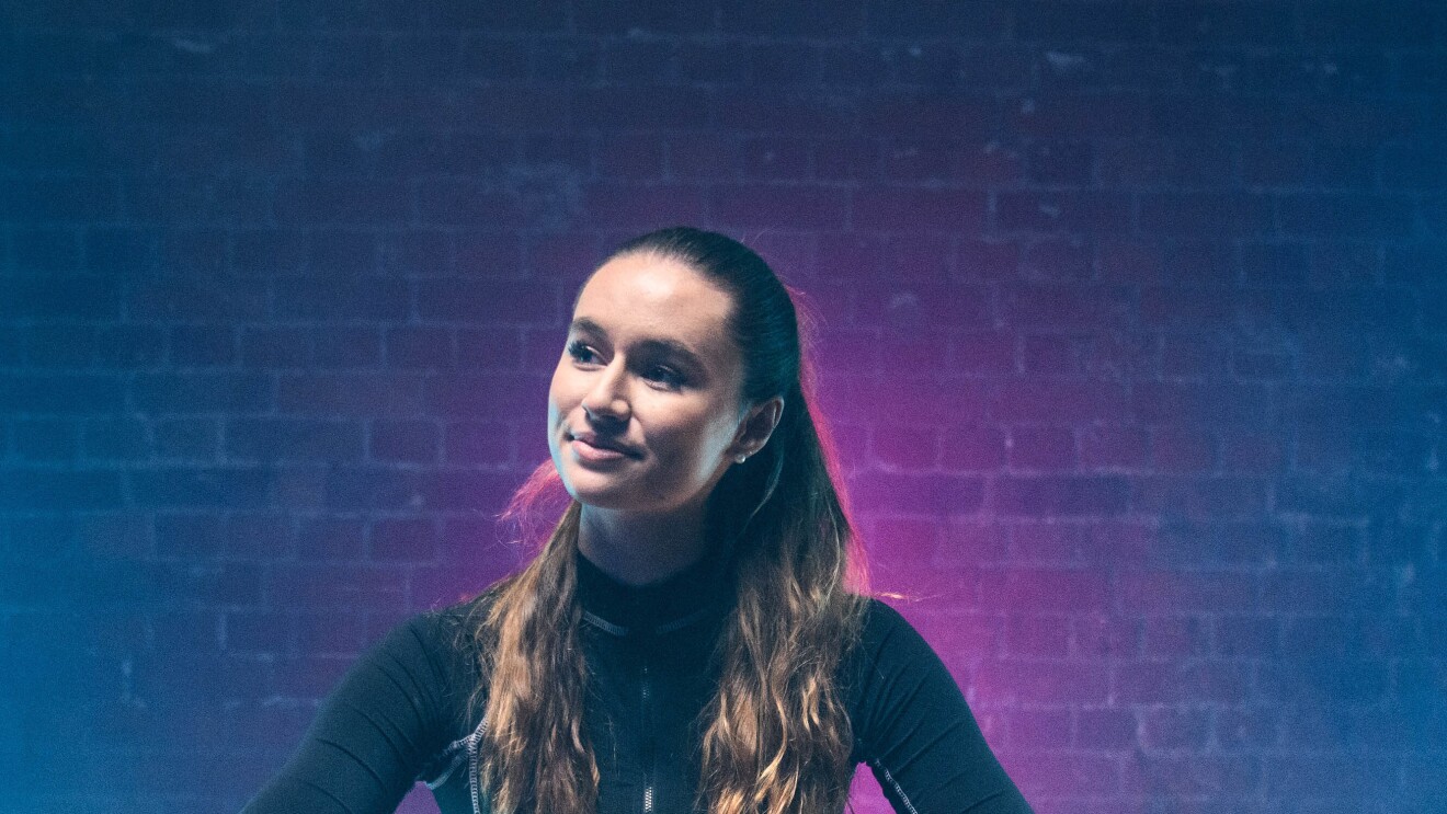 Lia Lewis crouching in a hall with a football which has the Amazon Smile logo