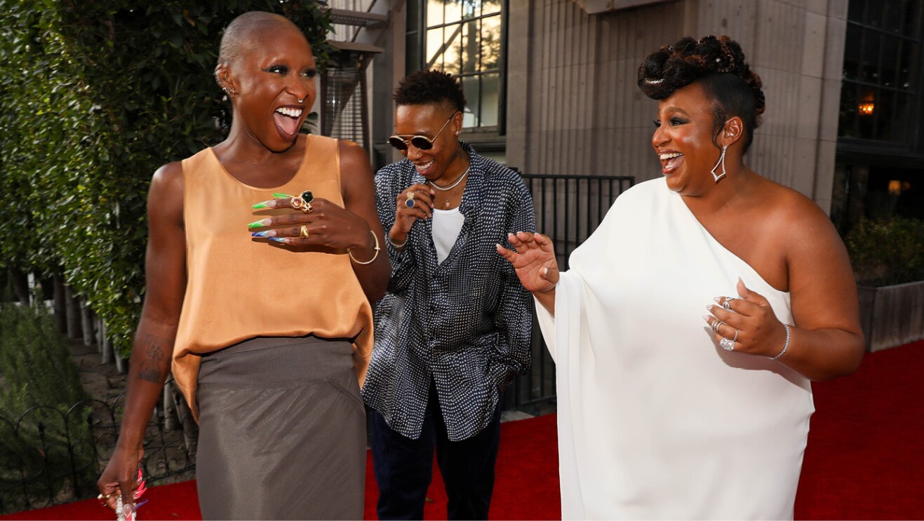 Two women smile and laugh while walking on the red carpet at the lord of the rings the rings of power premiere