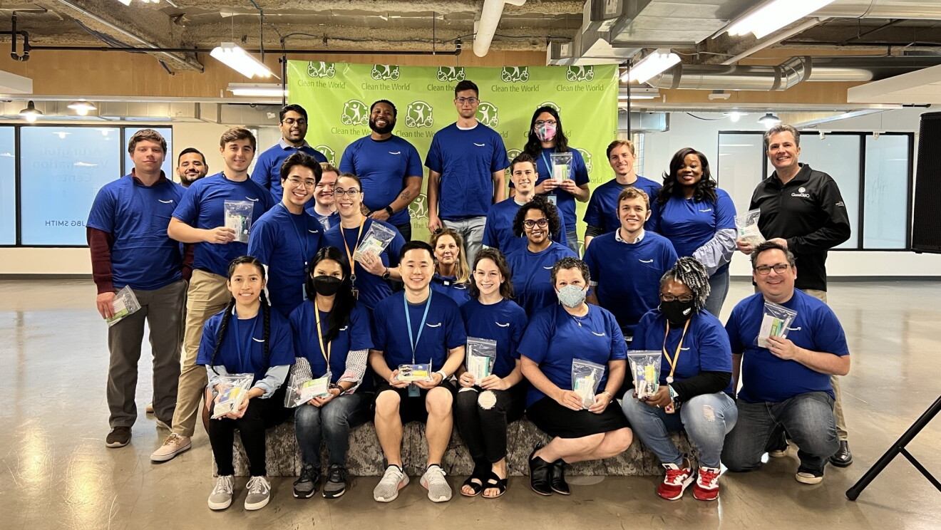 A group of Amazon employees wear blue Amazon T-shirts and hold hygiene packs to be sent to Ukraine.