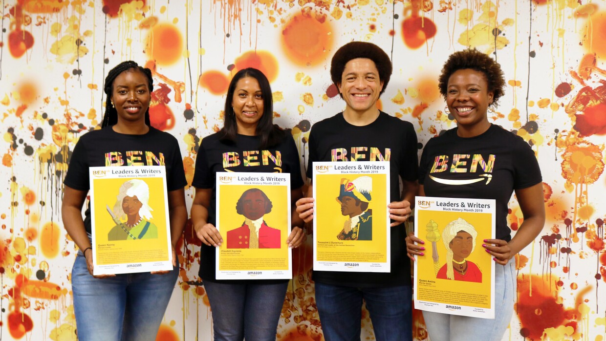 Picture of Amazon's Black Employee Network members holding posters of historic black figures (from left to right, Ramat Tejani with poster of Queen Nanny, Rebecca Wijeyesinghe with poster of Olaudah Equiano, Frederic Houinato with poster of Toussaint L‘Ouverture and Aisha Suleiman with poster of Queen Amina)