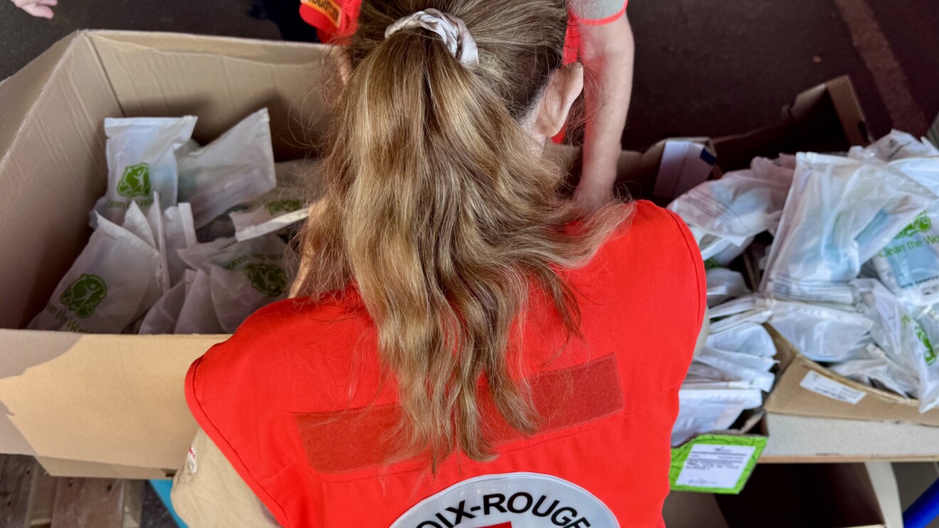 Red Cross volunteer sorting packaged meals into cardboard boxes
