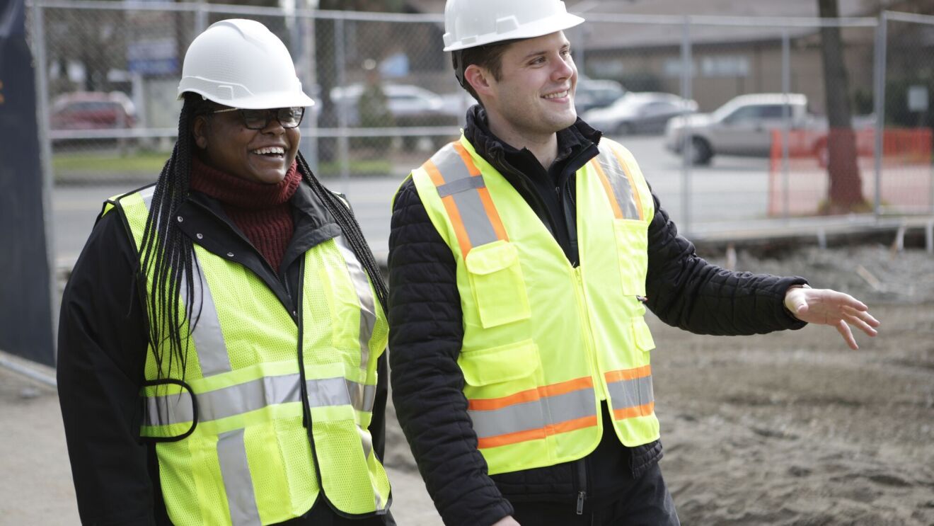 Two professionals in hard hats and hi-vis vests on job site