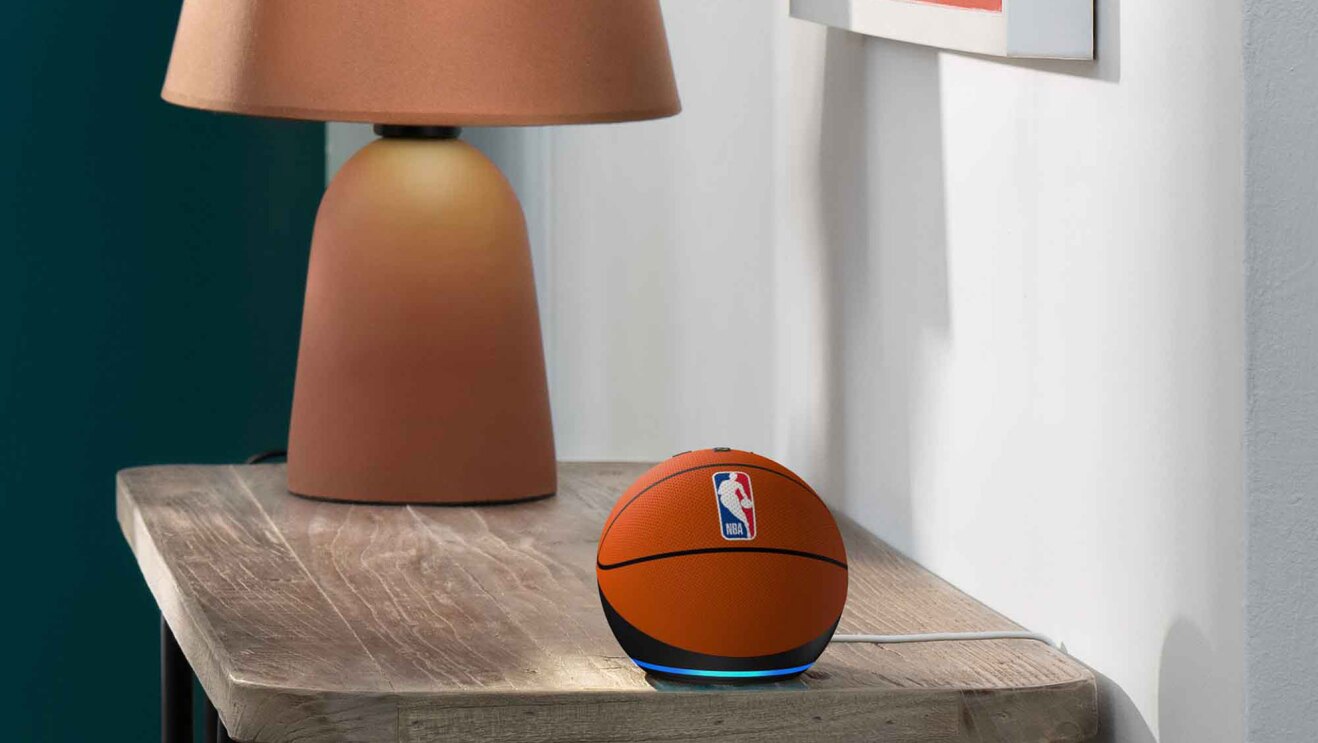 木製の家具の上に置かれた球状の小さなデバイスとランプ。デバイスはバスケットボールを模したデザイン。