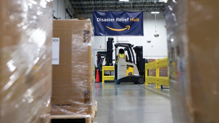 A photo of a forklift in an Amazon fulfilment center, lifting boxes of supplies to be sent for disaster relief.