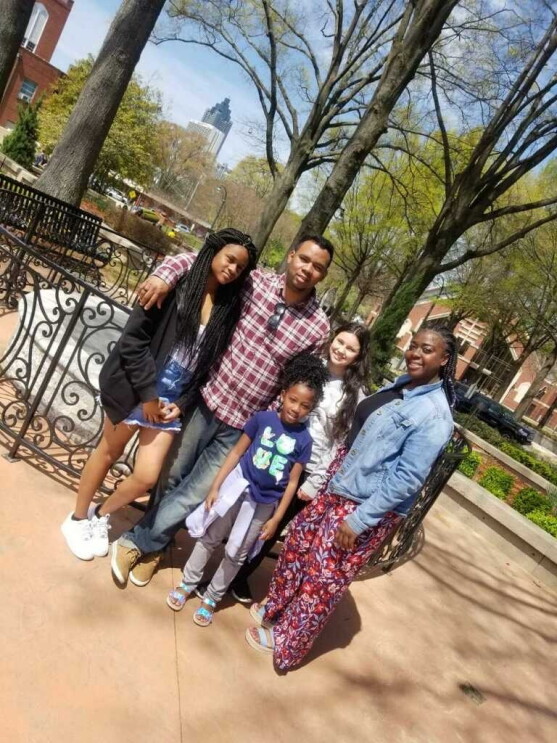 A man and his family stand in a park together