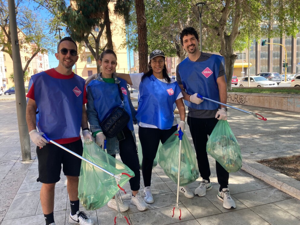 A group of Amazon employees is wearing blue vests and carrying tools to pick up garbage