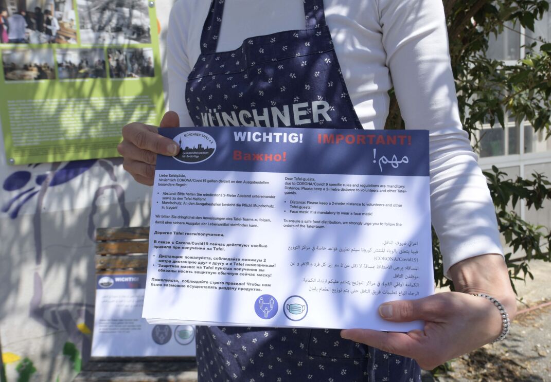 Mitarbeiterin der Münchner TAfel mit einem Informationshinweis.