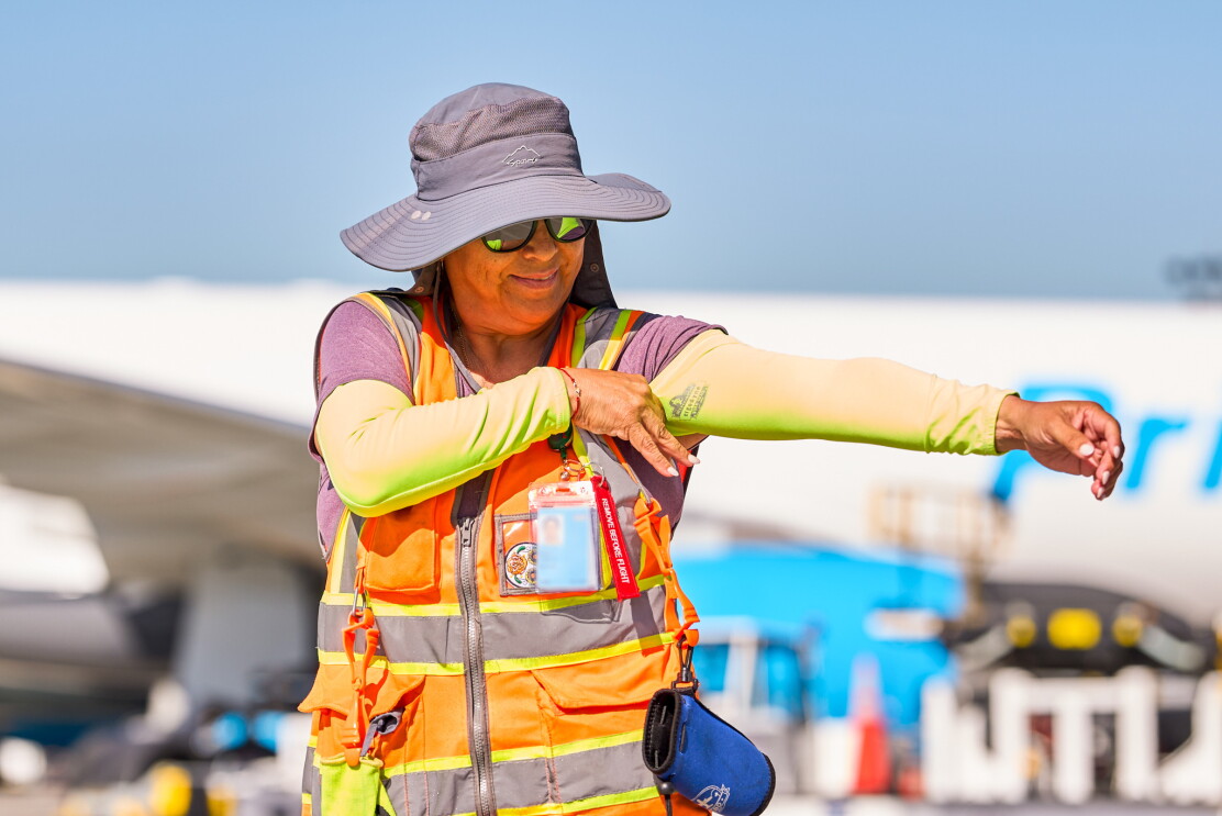 Amazon worker in safety vest and sun protection gear wearing cooling sleeves