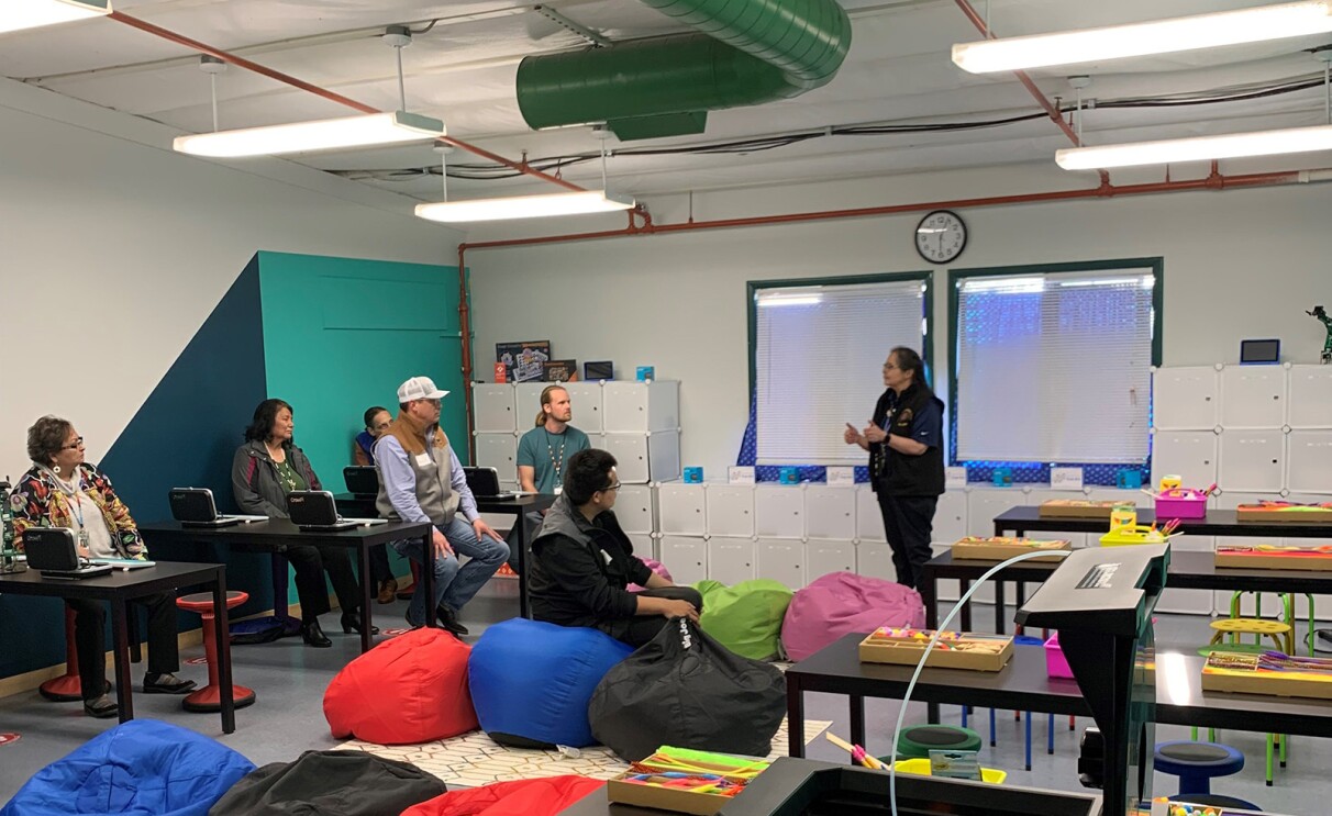 An image of adults sitting in a classroom listening to one person speaking at the front of the room.