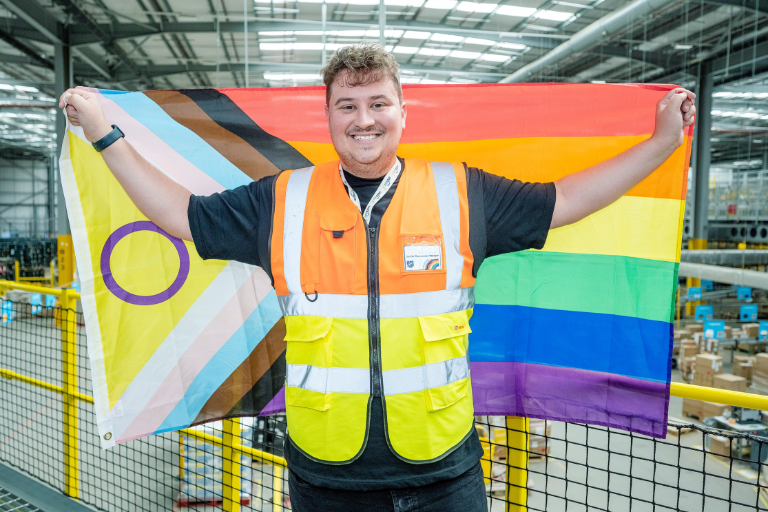 A man holding a Pride flag in a warehouse