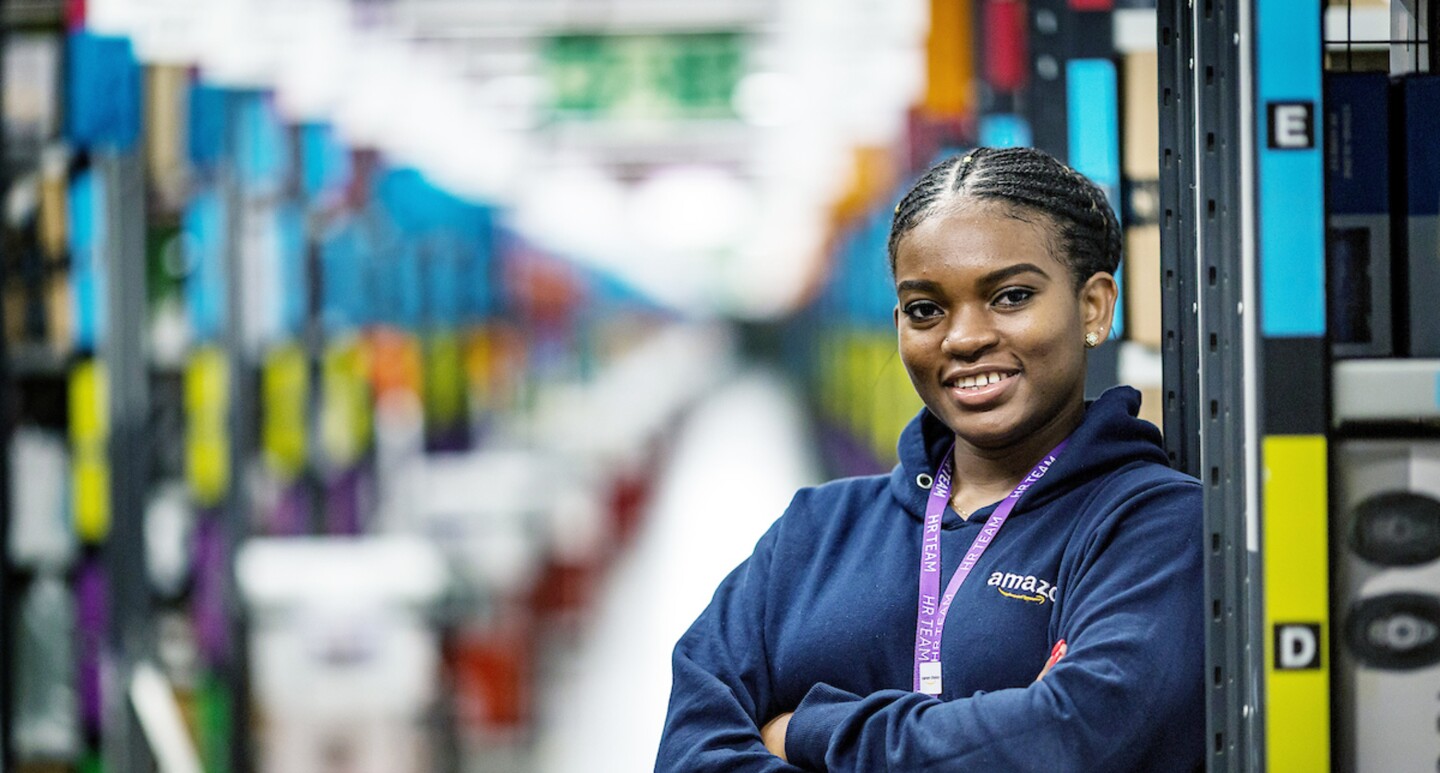 Joy Abaraye standing with her arms crossed in a fulfilment centre.