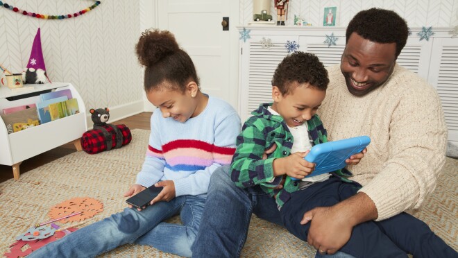 一家人坐在地毯上愉快地观看亚马逊的设备。