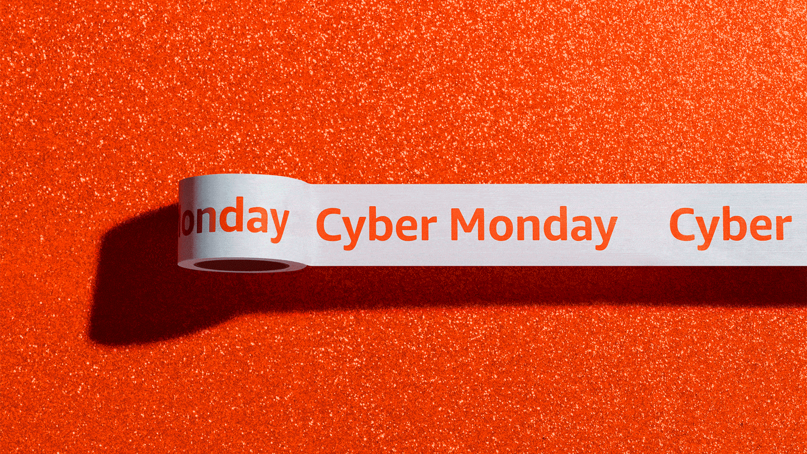 A roll of white packaging tape with bright orange font that reads "Cyber Monday" is set on a bright orange backdrop.