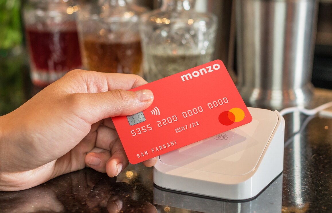 hand holding coral Monzo bank card over a white Apple pay machine