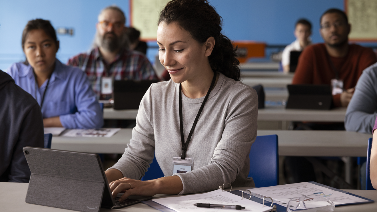 An Amazon employee works on her laptop in a classroom with other students.