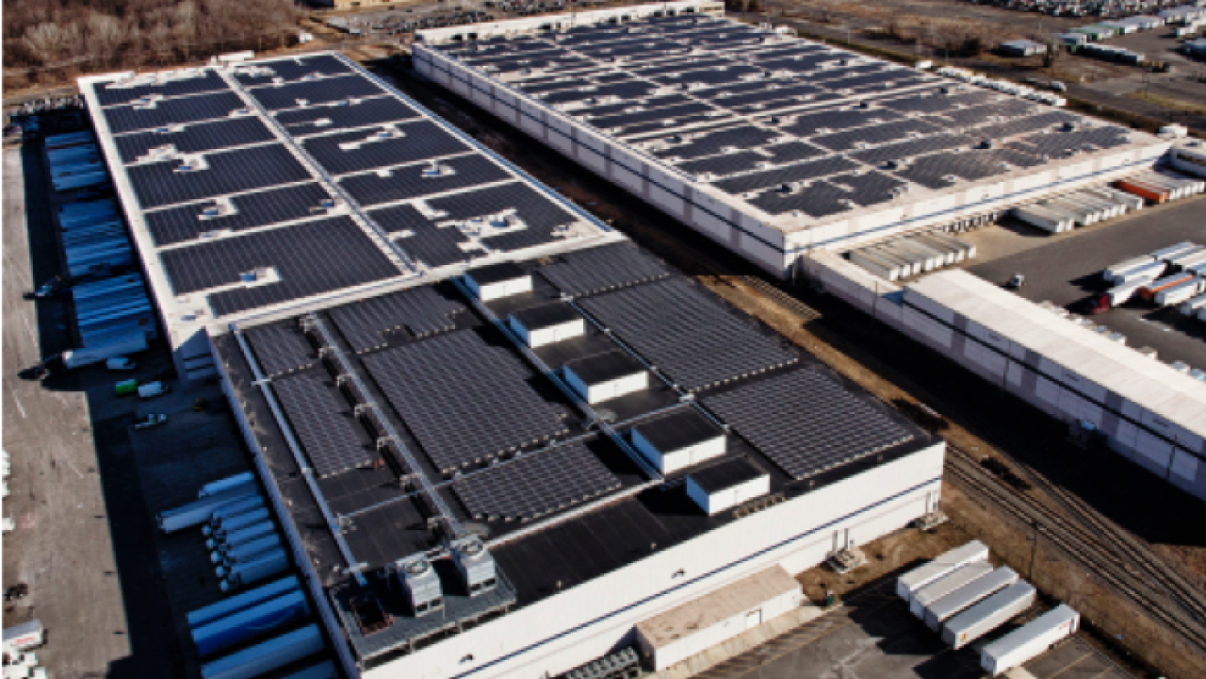 Aerial view of of two Amazon fulfilment facilities with solar systems on their rooftops.