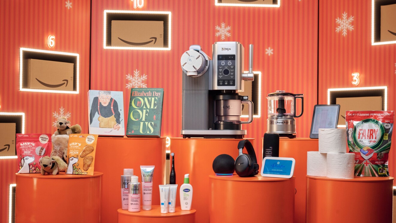 Amazon Black Friday product range, including devices, pet products, books, and toiletries - all on orange tables against a festive amazon background