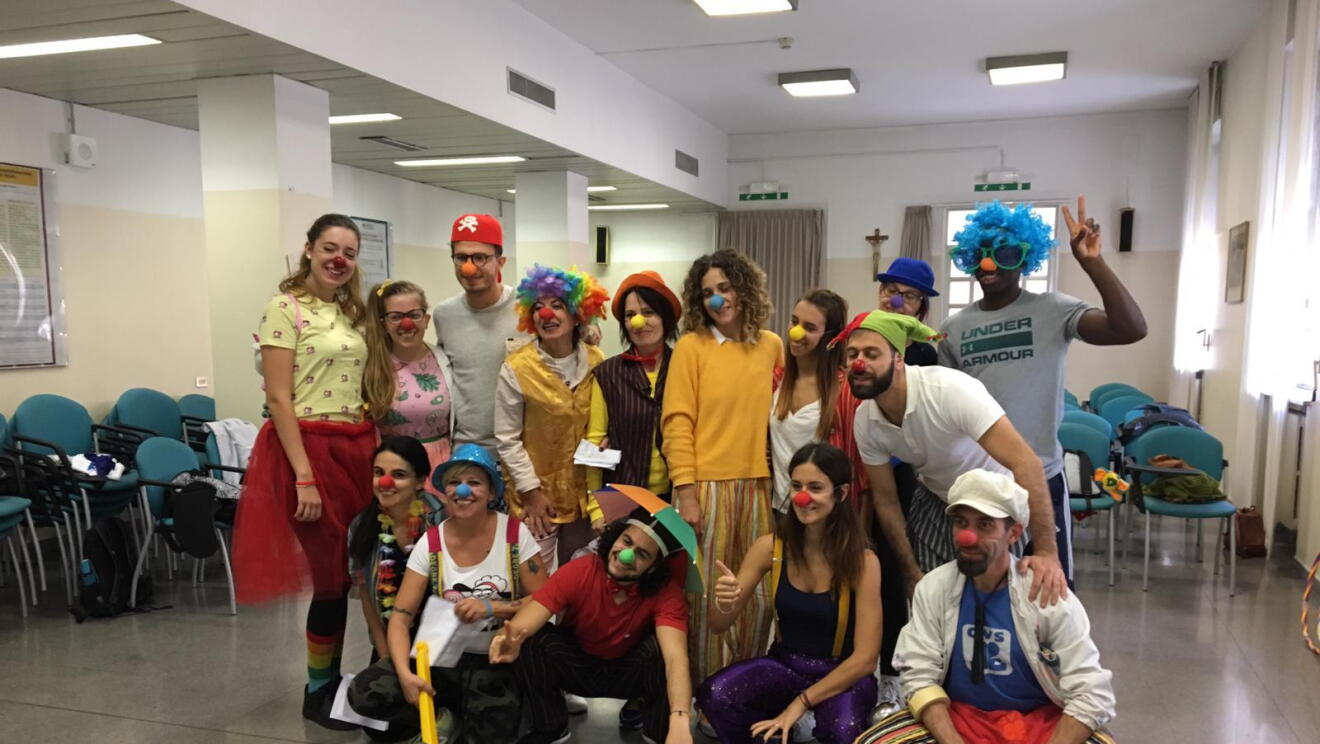 Dipendenti Amazon in gruppo durante il corso di clown terapia. Sono travestiti da clown e indossano nasi di gomma rossi. 