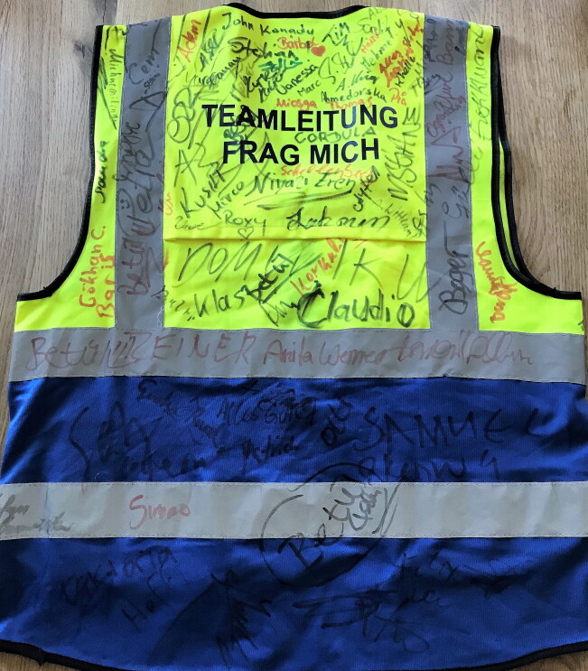 Mamadous Sicherheitsweste von hinten mit vielen Unterschriften von Kollegen.