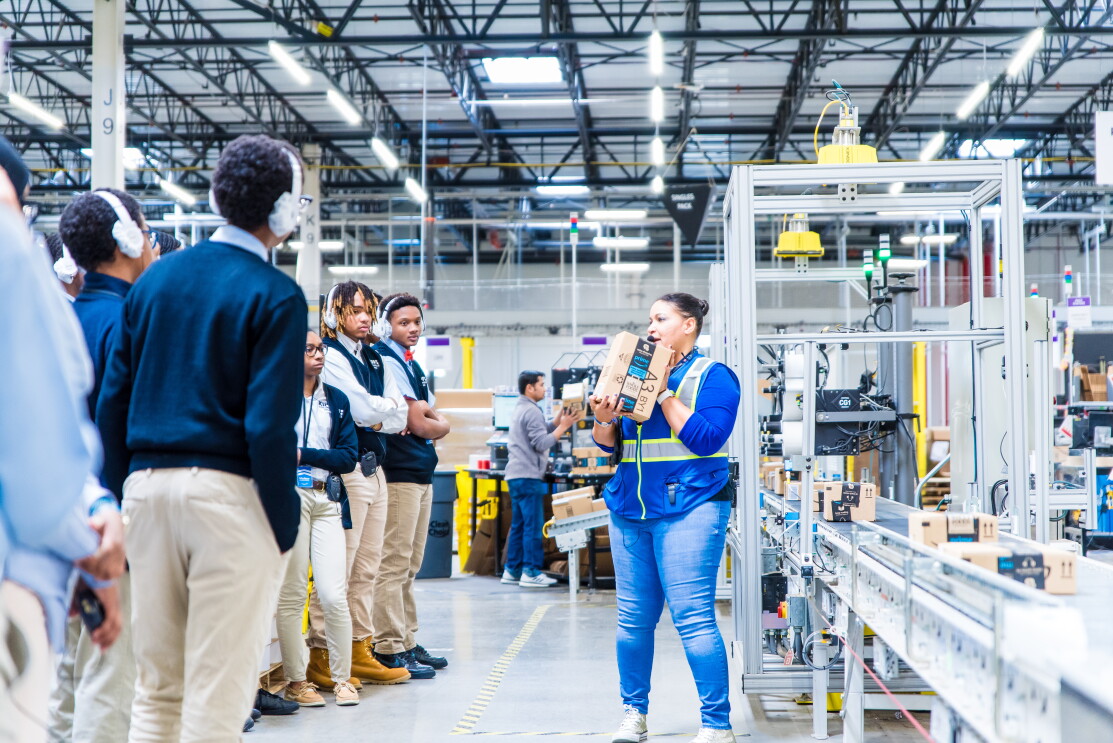 Students attend a tour of an Amazon robotics fulfillment center