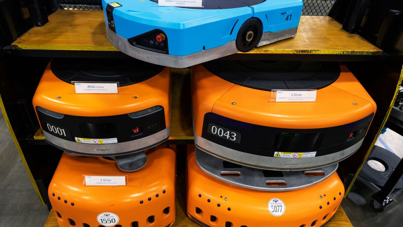 Amazon's robotic fleet showcased in a fulfillment center display, featuring a Hercules robot on the top shelf