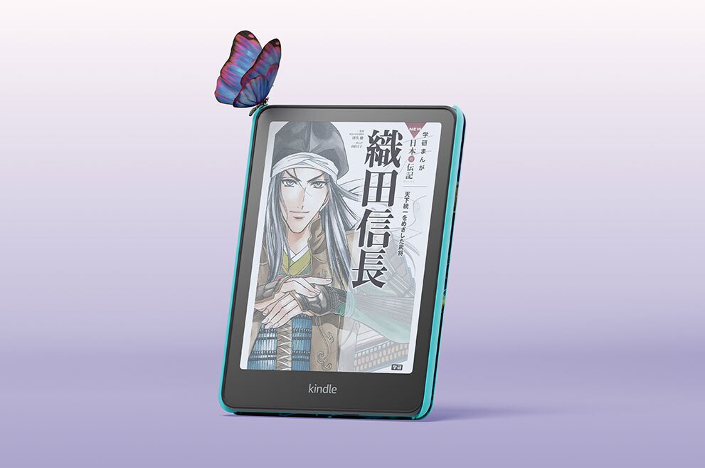 薄紫のグラデーション背景、中央にKindle Colorfosfキッズモデルが置かれている。画面は「織田信長」の書籍表紙で、武士姿のキャラクター絵が見える。端末の左上に蝶がとまっている。