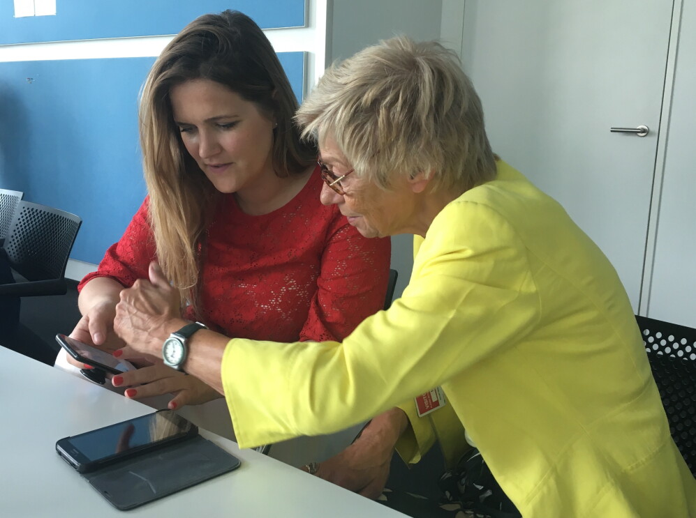 Eine  junge Frau erklärt einer älteren Dame, wie ein Smartphone funktioniert