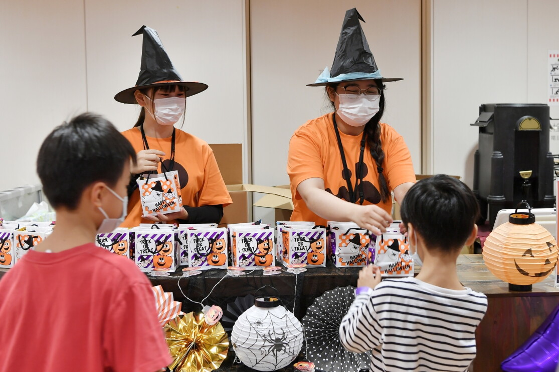 魔女の帽子をかぶったスタッフからお菓子をもらう子どもたち