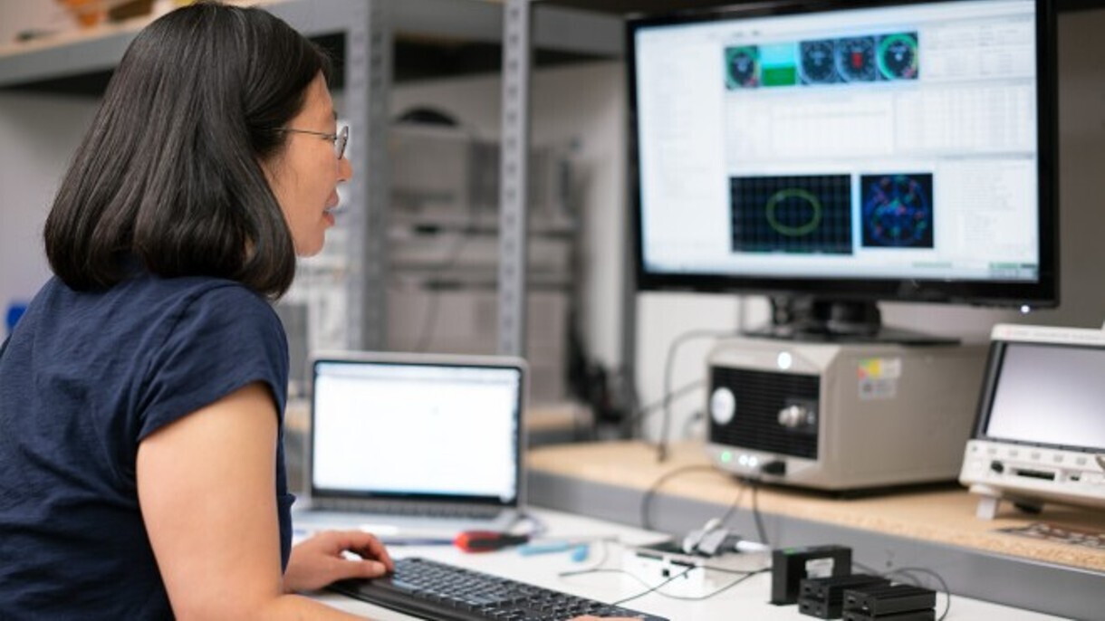 Amazon robotics employee Lisa works at her desk with various screens and equipment.