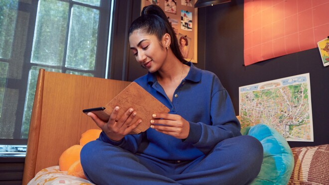 一名女子坐在沙发上阅读,手里拿着kindle阅读器