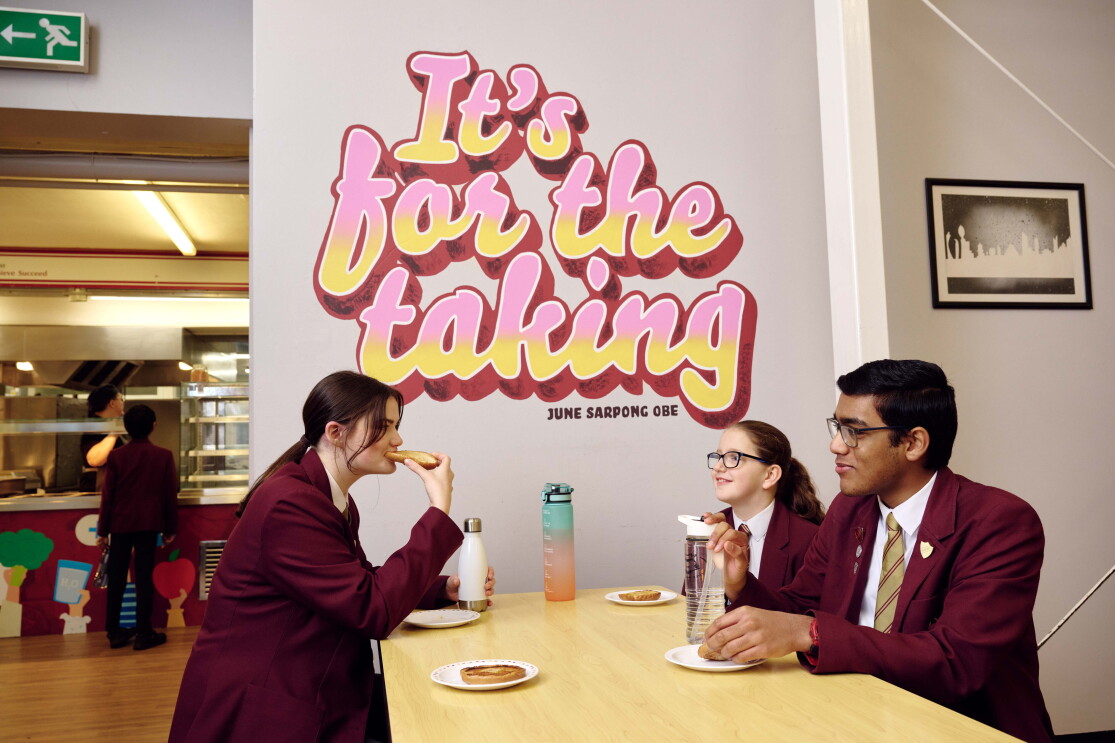 Student eat lunch in front of a June Sarpong quote