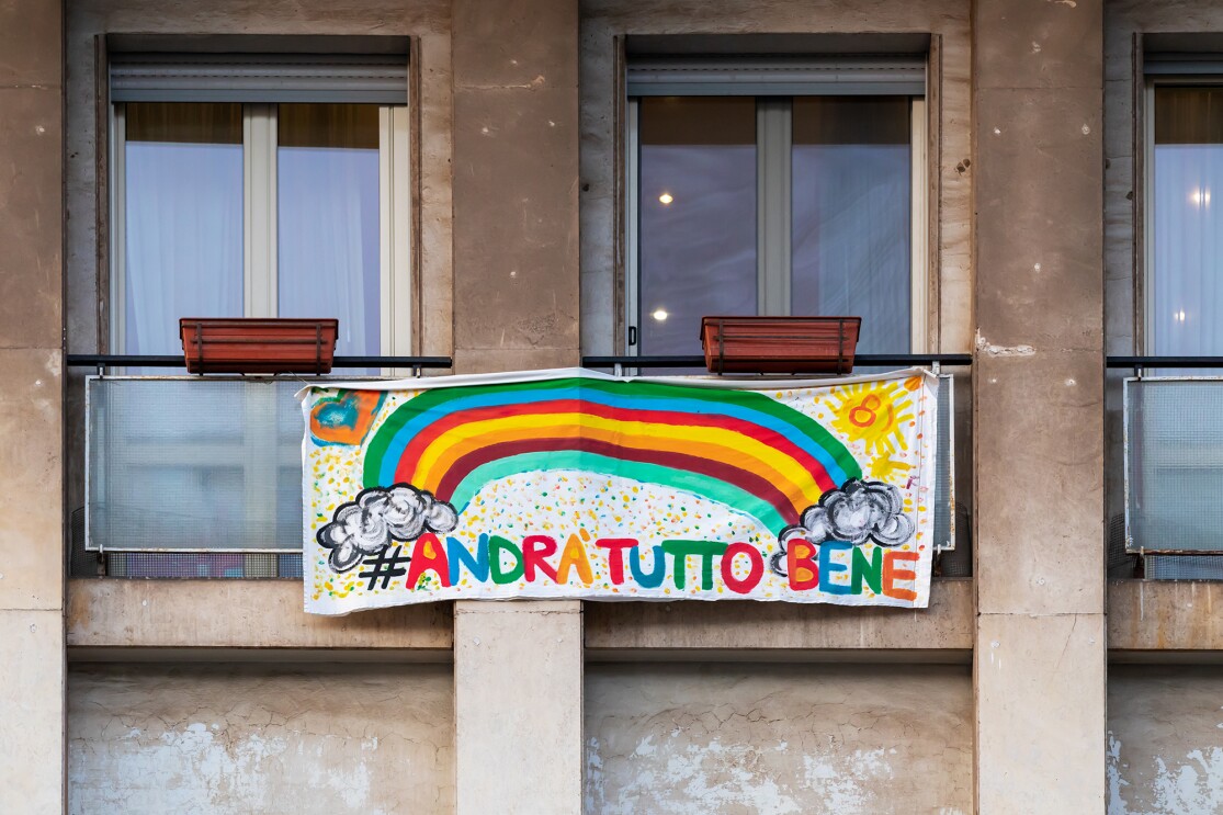 A child placing homemade rainbows in the window of their home, during COVID-19 pandemic.