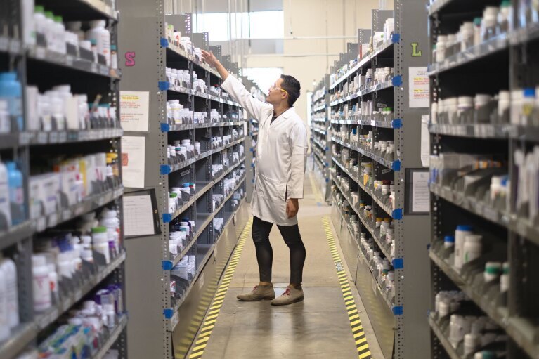 Pharmacist stocking shelves in drug store aisle