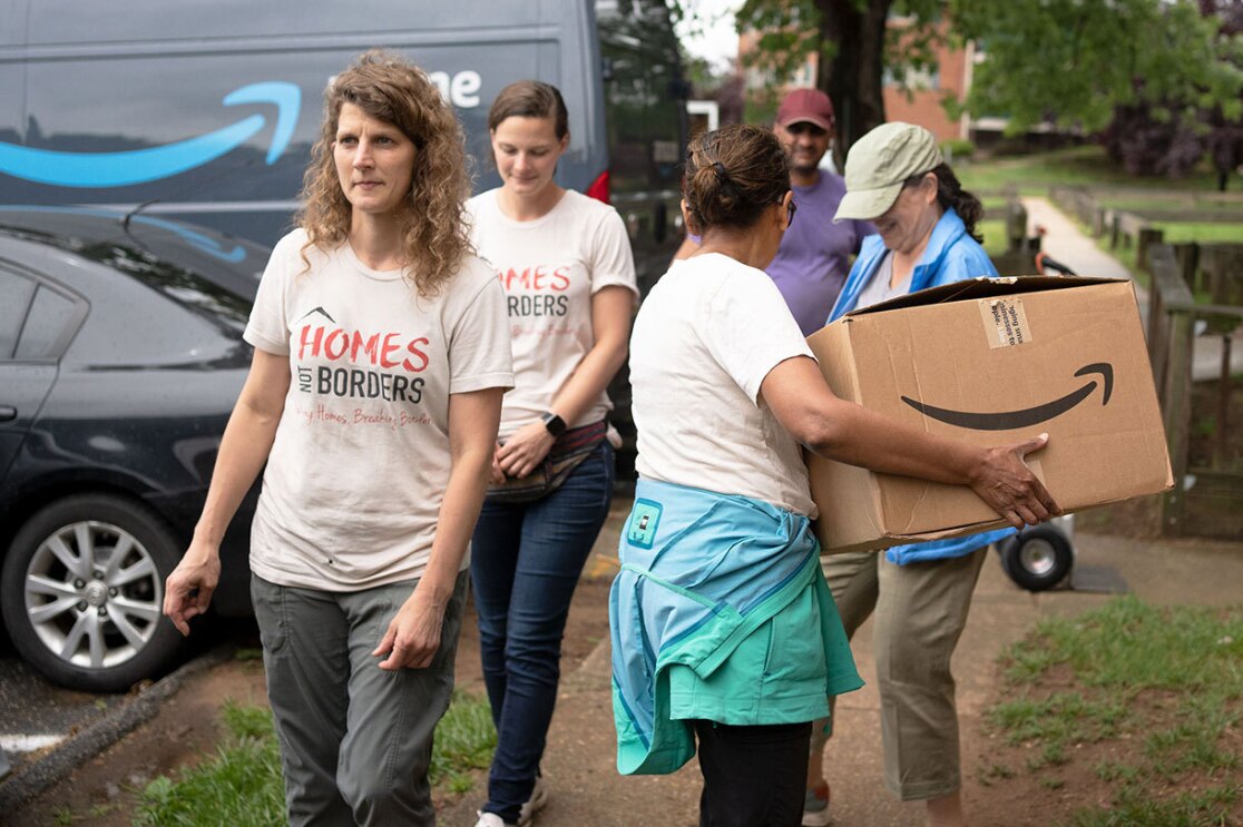 Volunteers and Amazon employees load up Amazon delivery vans with essential furniture and household products.
