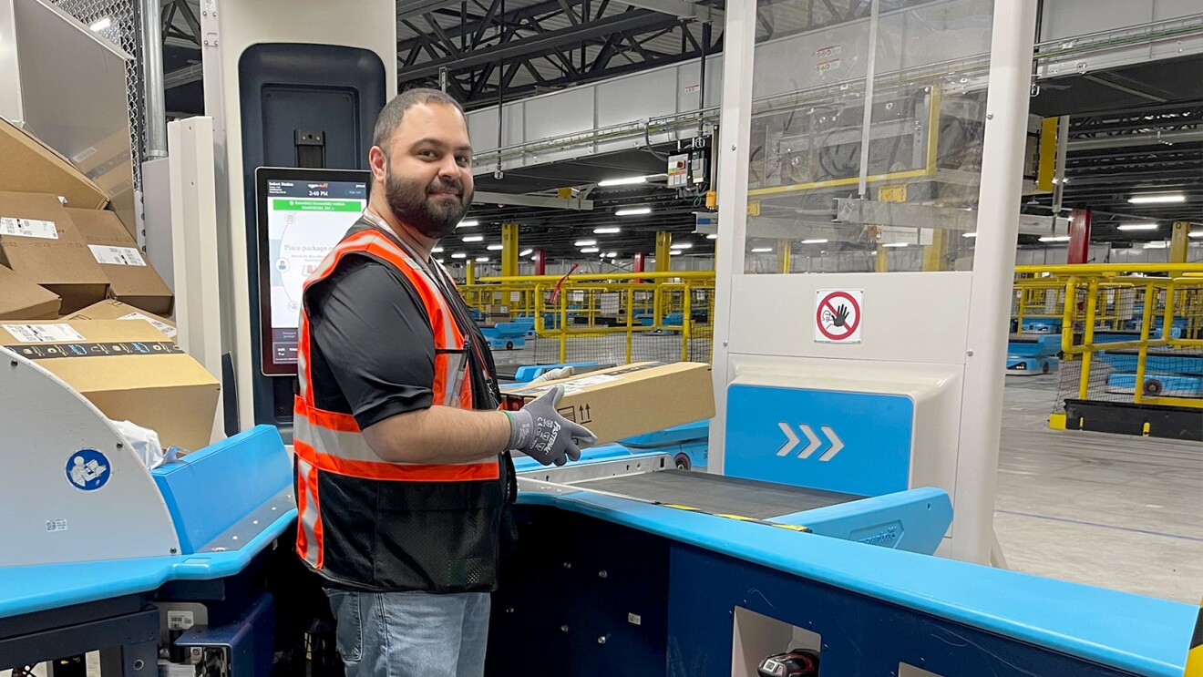 Image of an Amazon employee in a fulfillment center holding a package.