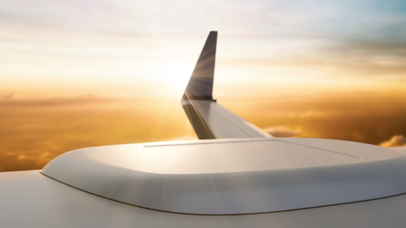Airplane wing silhouetted against golden sunset sky