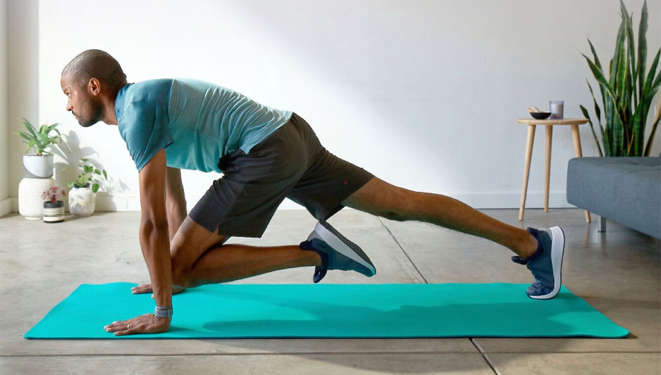 A man working out at home using a green yoga mat. 