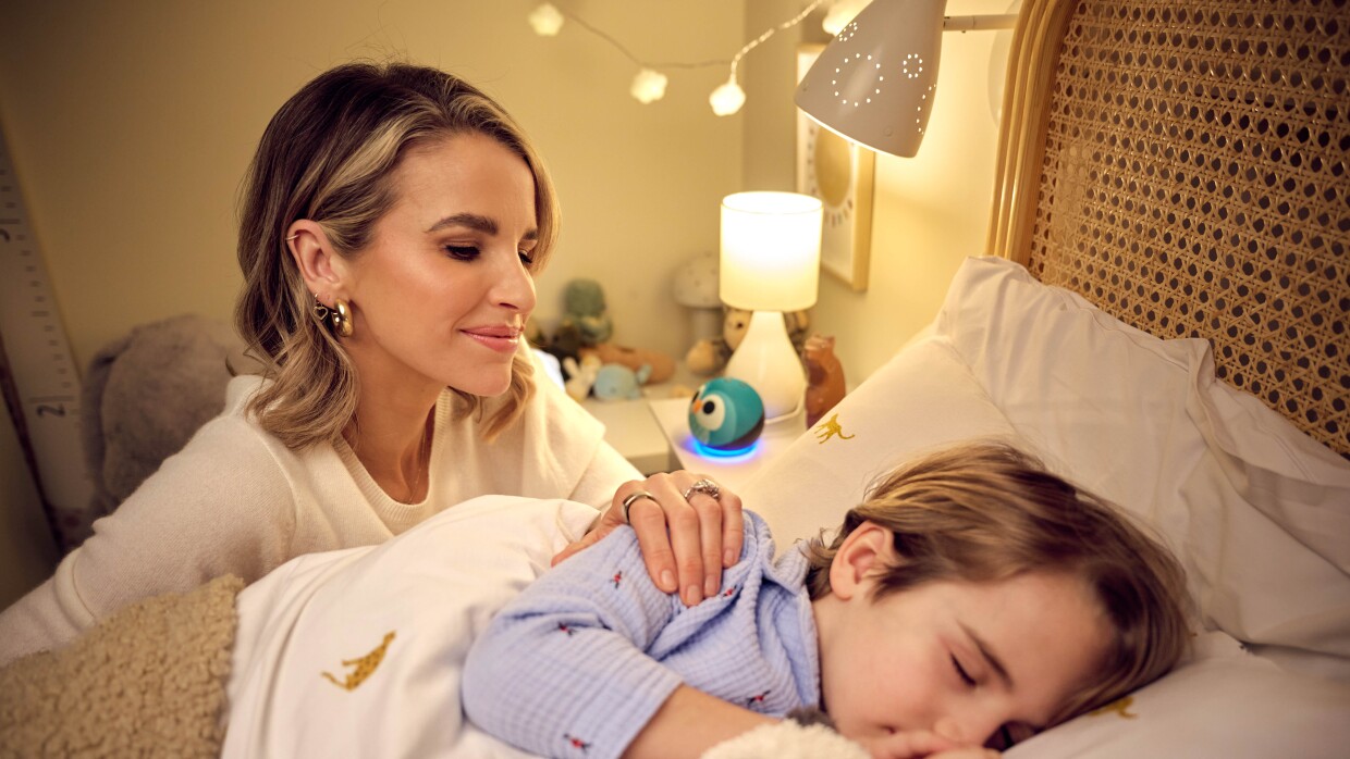 Vogue Williams puts her child to bed, with an Amazon Alexa device in the background