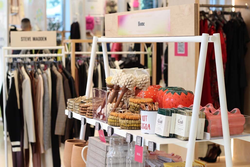 An image of a display of Home products in the Amazon Style store. There are cool strawberry shaped cases, room scents, and loofas.