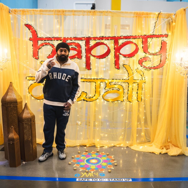 Nattan debout devant un panneau sur lequel est écrit « Joyeux Diwali »